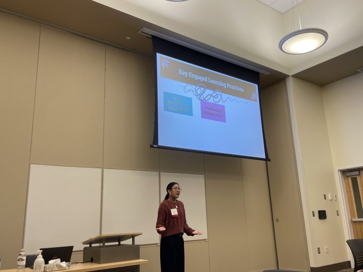 Corine Ayesha Ebora stands in a room with a presentation above her head