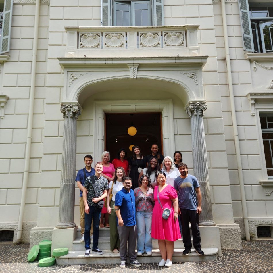 A group of people pose in front of an off-white building