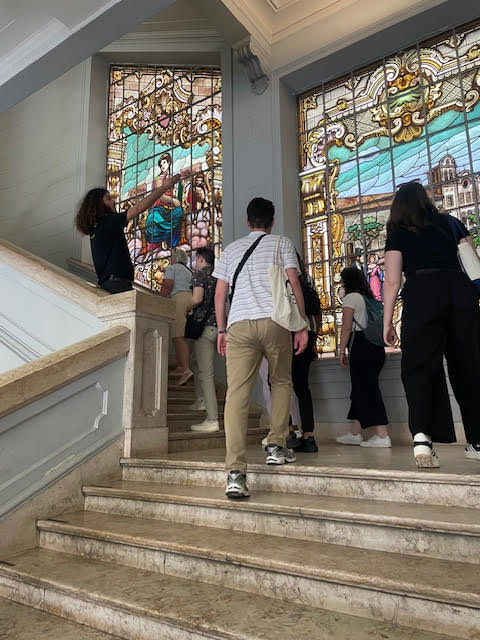 A groupi of people walk up steps in a building with stained glass