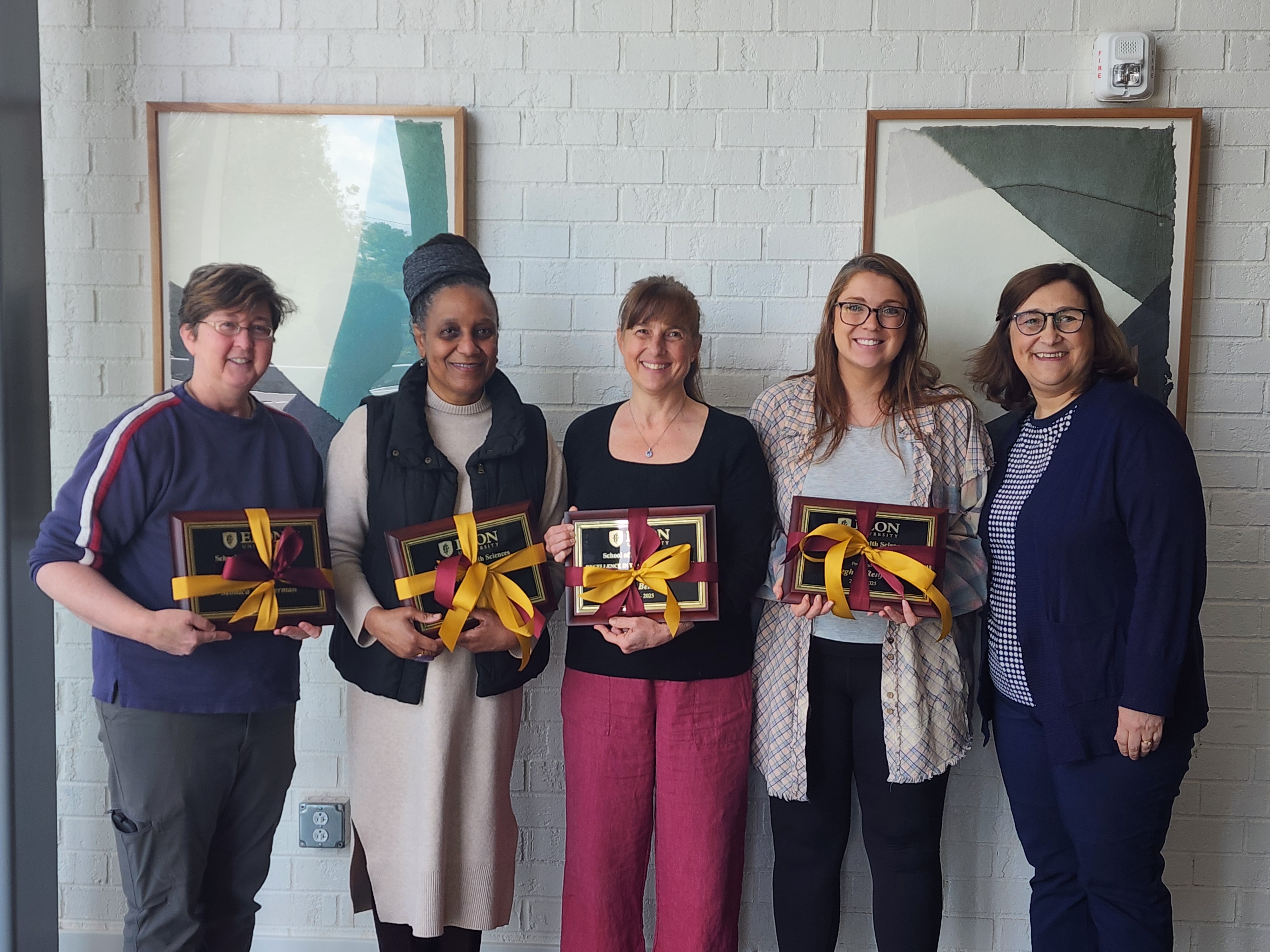 Five people hold awards in a line