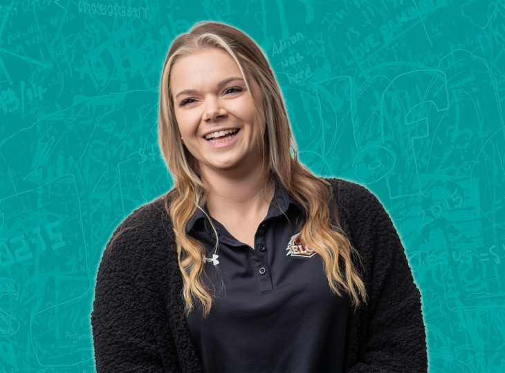 A woman smiles in front of a turquoise backdrop with a graffiti-style pattern