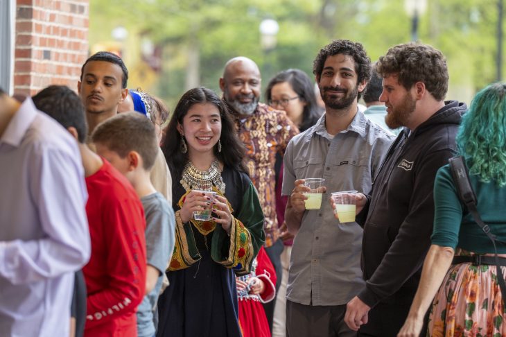 Group of diverse people at an outdoor social gathering, smiling and holding drinks.
