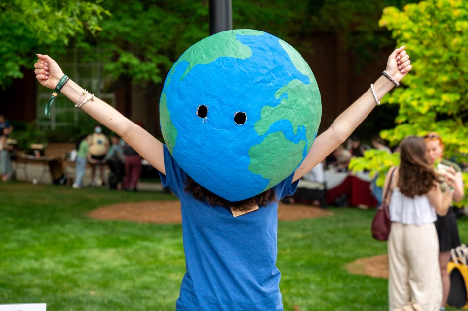 A person wearing a globe on their head with their arms outstretched.