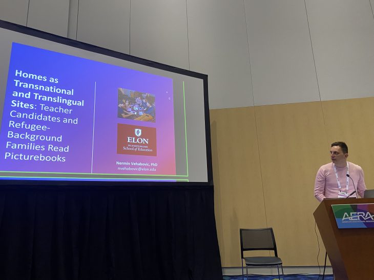 A man stands at a podium next to a presentation screen