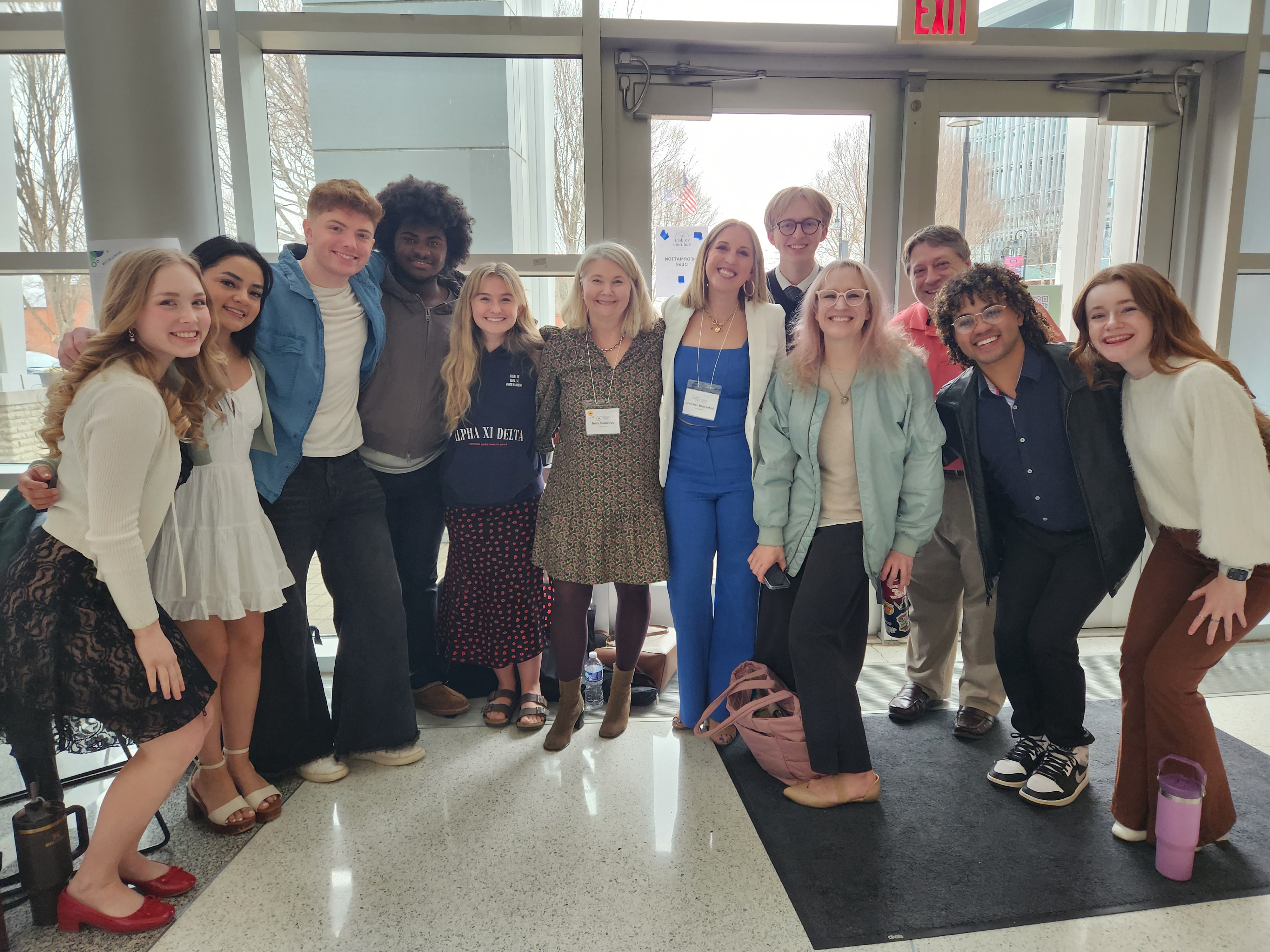 A group of people pose for a photo in front of glass windows