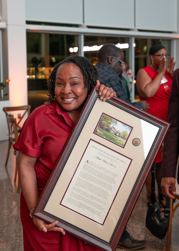 Akilah Weaver Hill ’00, a recipient of the 2025 Distinguished Alumni Awards, poses with his award after the ceremony on the Elon University campus
