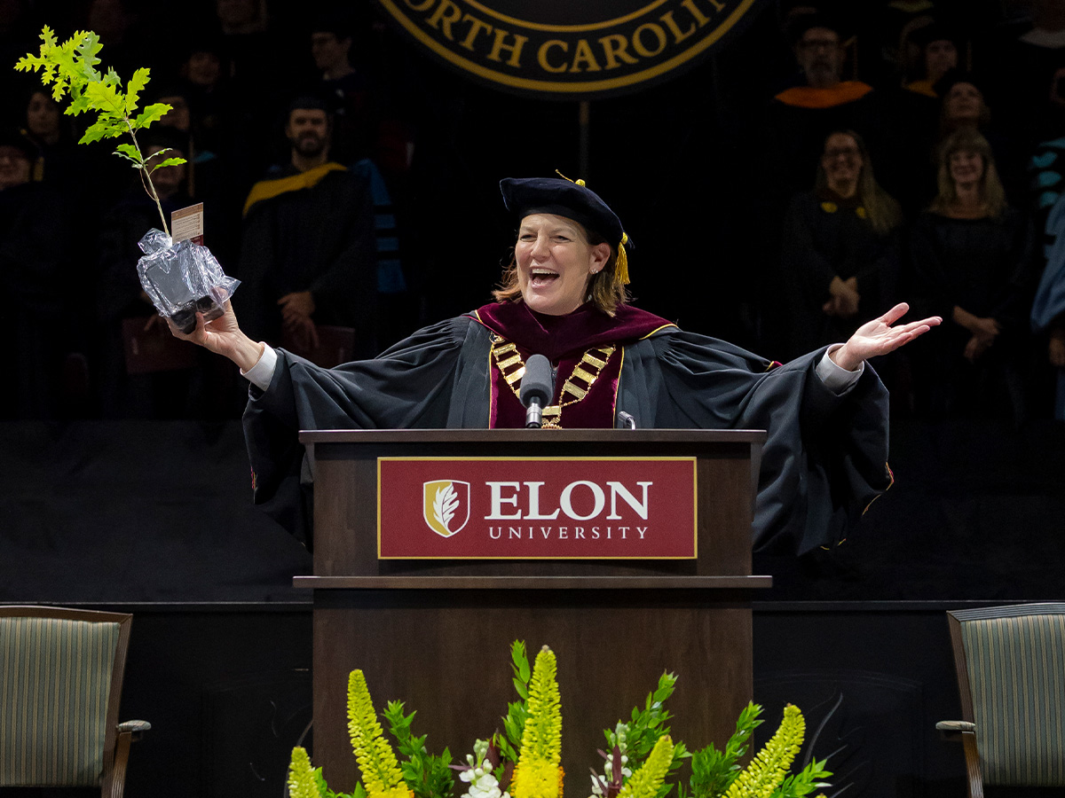 Elon University President Connie Ledoux Book smiles widely while holding up a symbolic oak sapling gift during her Commencement address.