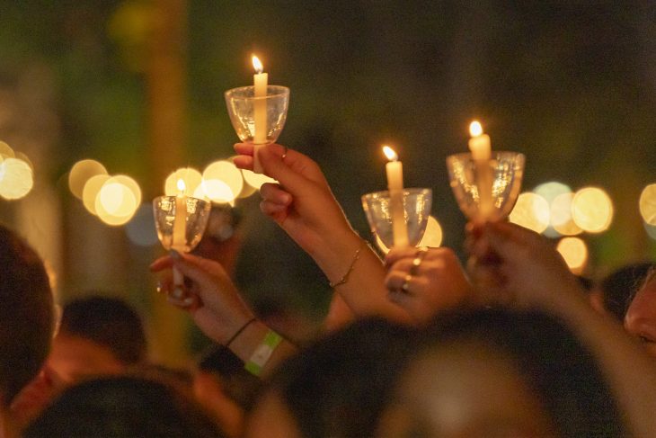 Students raise glowing candles into the night sky during Elon’s Numen Lumen ceremony, symbolizing shared light and reflection.
