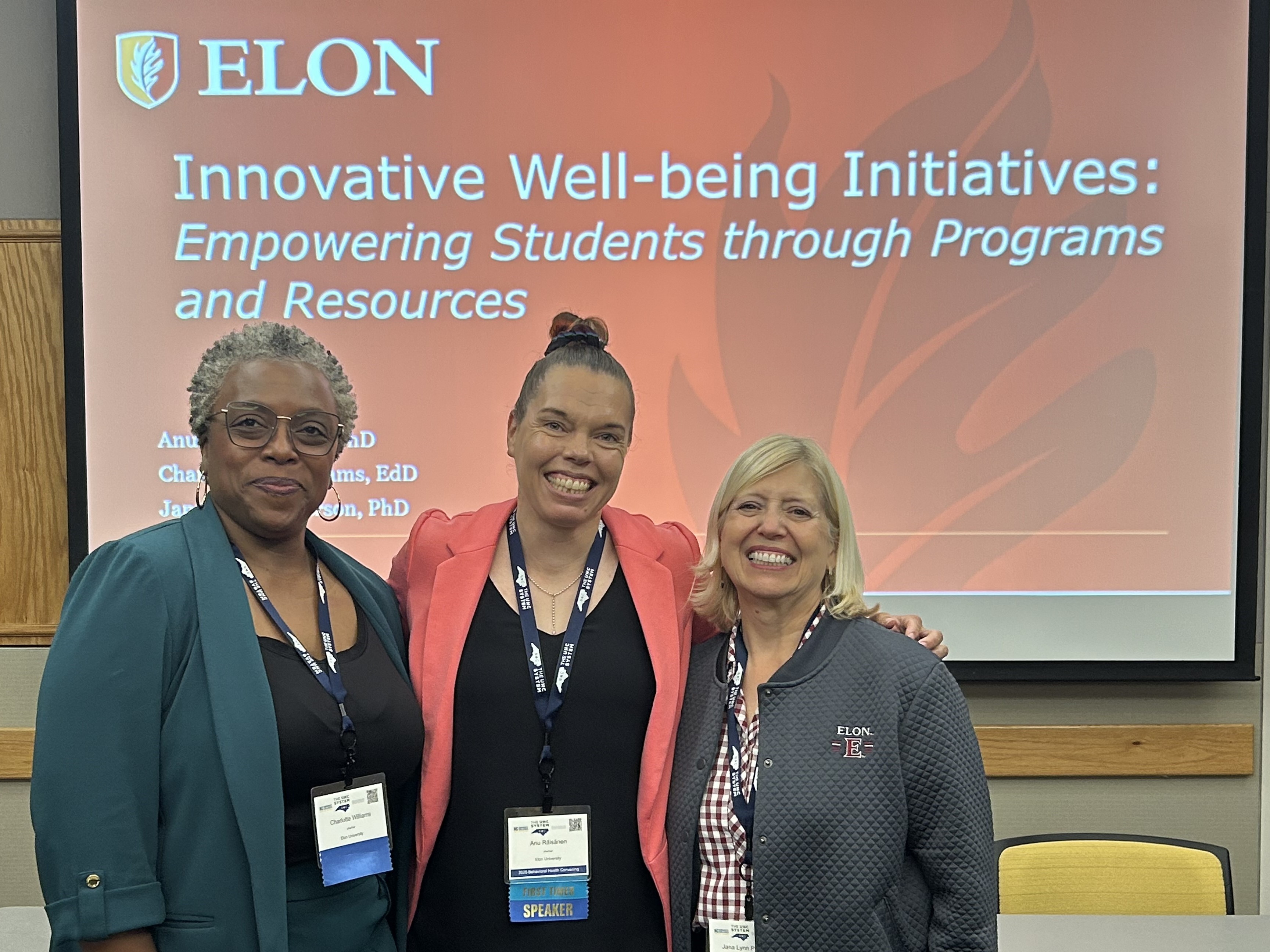 Three women smile in front of a presentation slide titled ‘Innovative Well-being Initiatives: Empowering Students through Programs and Resources.