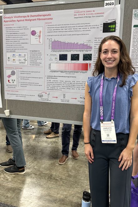 A young woman stands next to a poster presentation