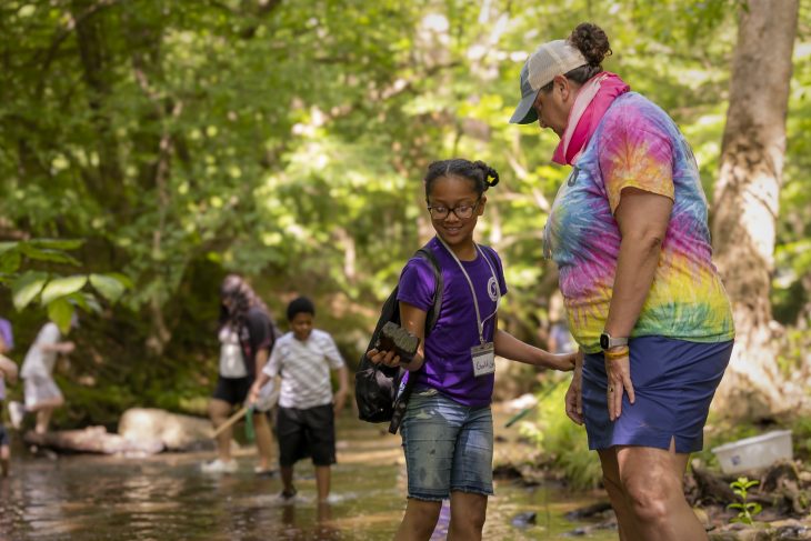 Jenn Russell ’98, a middle-school teacher, works with a student in a creek at Cedarock Park in Burlington, North Carolina