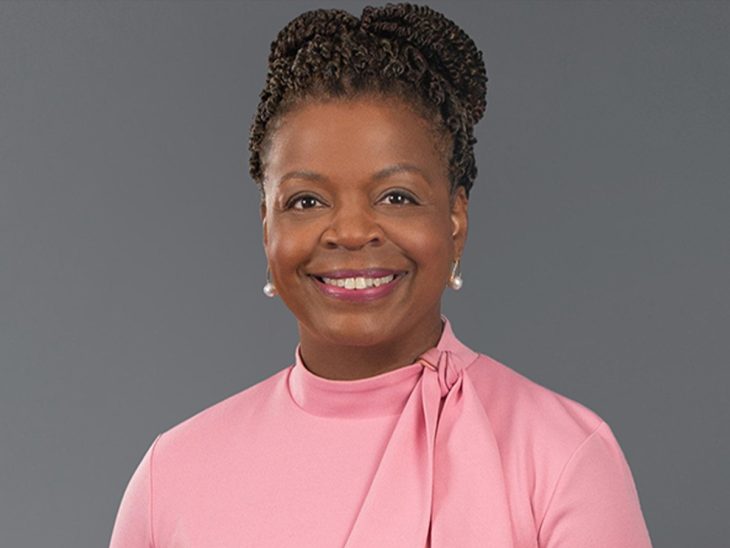A headshot of a woman in a pink blouse smiling at the camera.