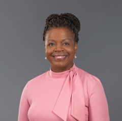 A headshot of a woman in a pink blouse smiling at the camera.