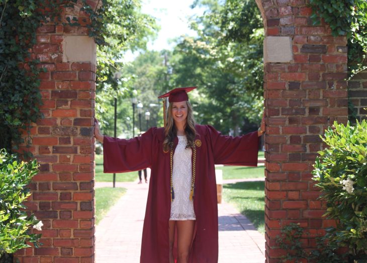 Alumna Taylor Casey '16 in her graduation attire on Elon University's Campus