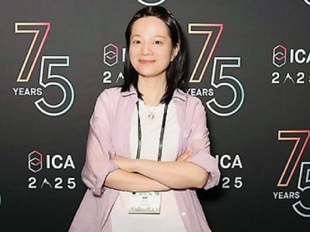 Jenny Jiang stands in front of ICA poster.