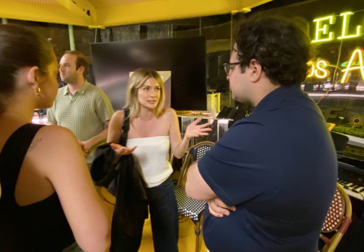 A woman gestures expressively while talking with others in a casual networking setting.