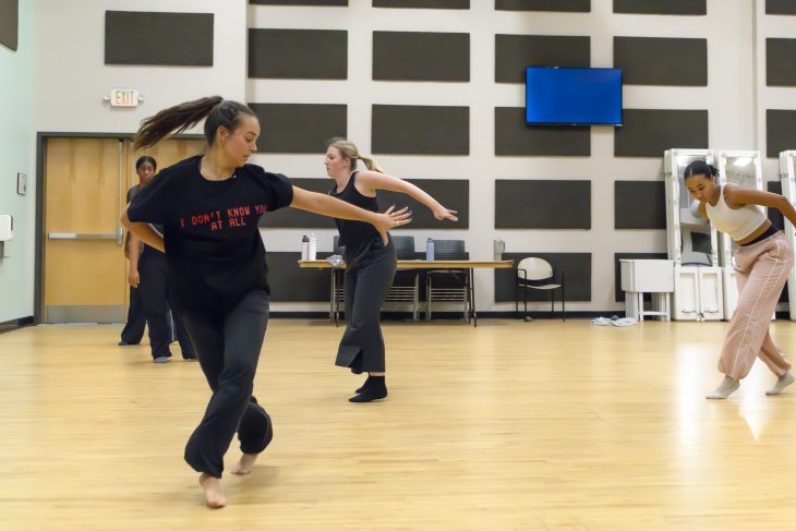 A dancer, Lila Snodgrass, moves gracefully during a rehearsal, with another dancer in the background.