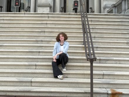 A young woman sits on steps and poses for a photo