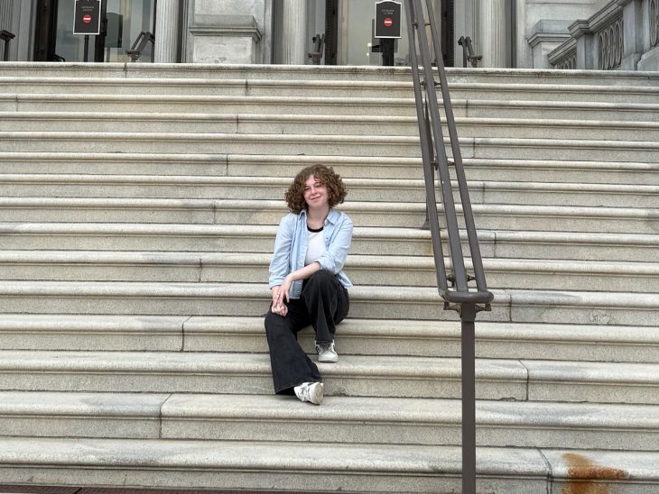A young woman sits on steps and poses for a photo