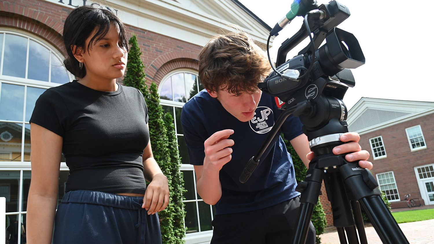 EJP students Mariana Prieto and Chase Slesinger-Hall hover over a camera.