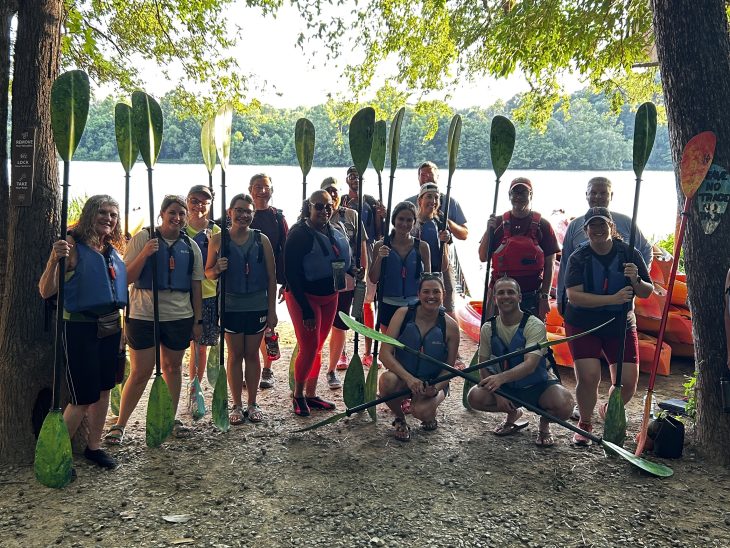 Group gathered on the shore with paddles