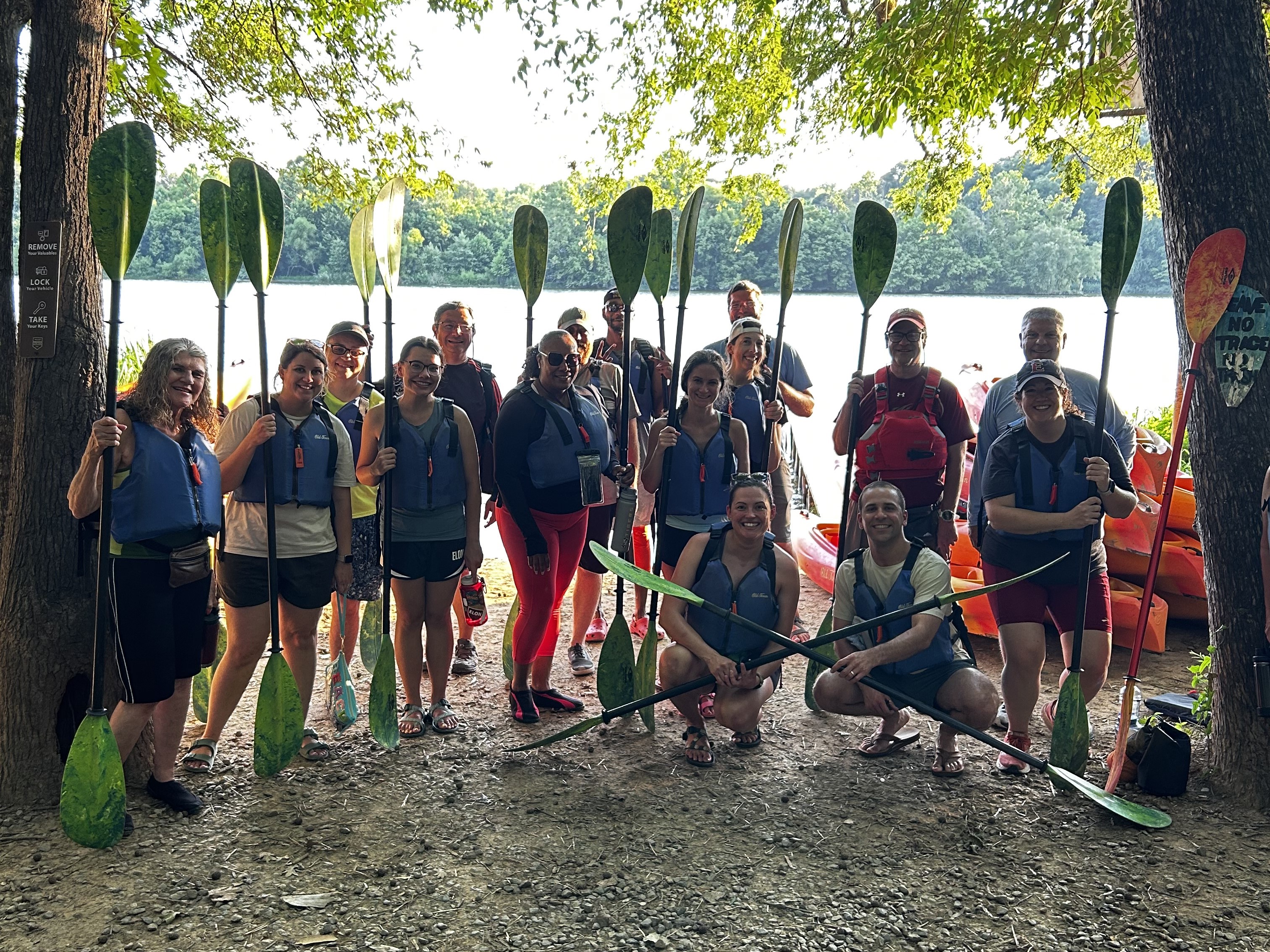Group gathered on the shore with paddles