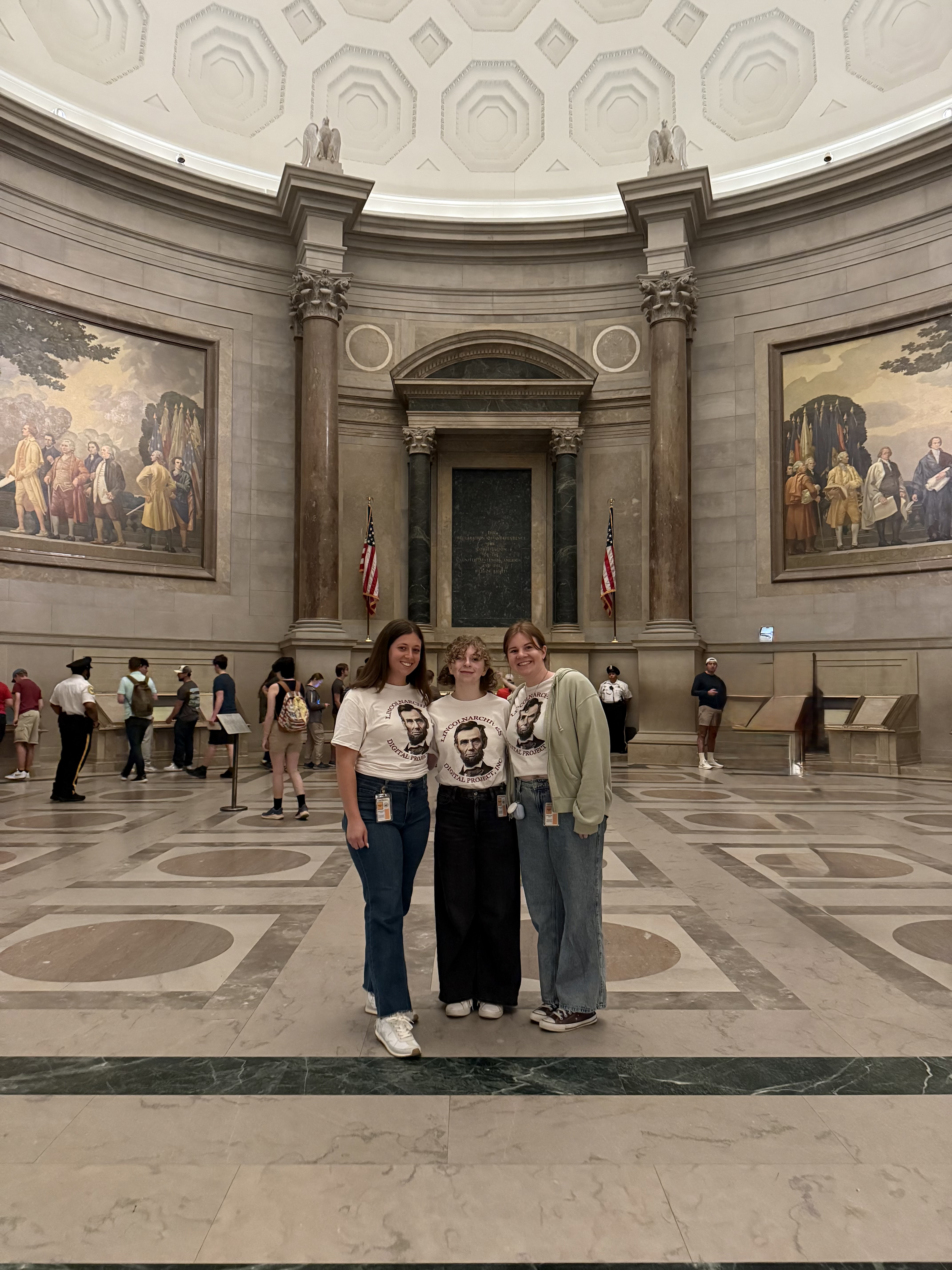Three people pose in the National Archives