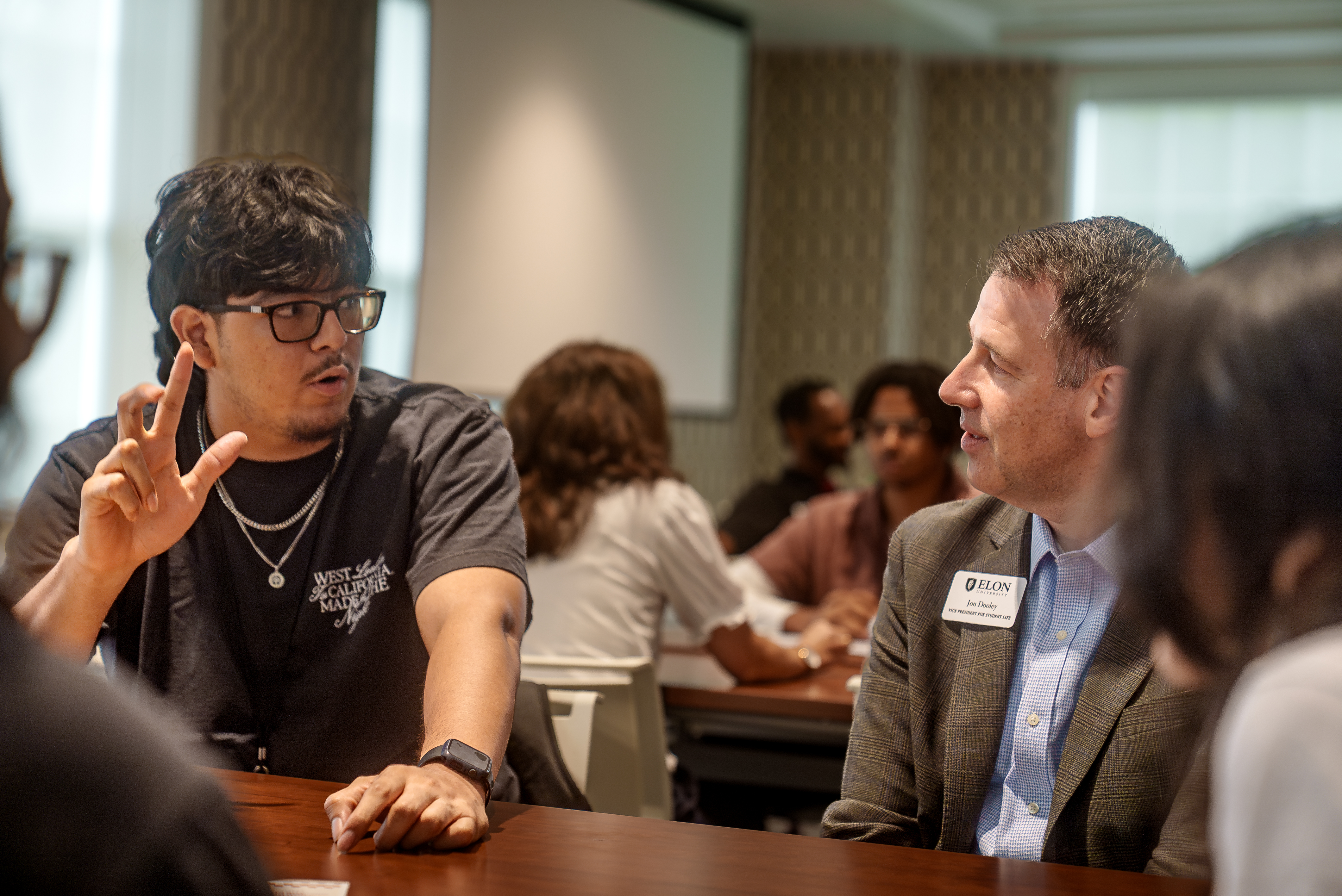 A student animatedly talks with an Elon representative during a roundtable discussion.
