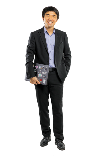 A portrait of a man in a business suit smiling and holding a laptop.