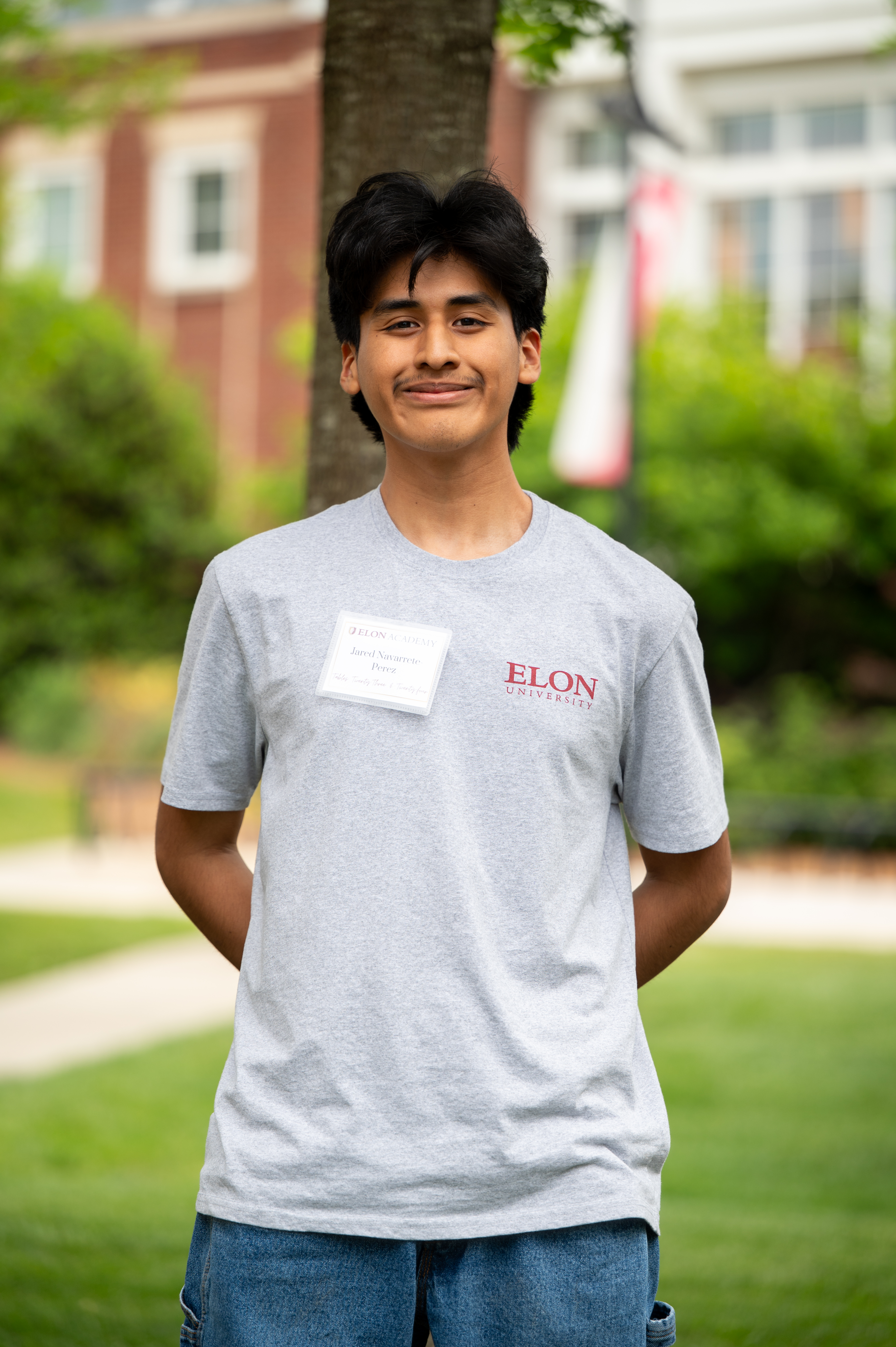 Photo of Jacob Navarrete Perez in front of a green background. He is wearing a t-shirt with the Elon University logo
