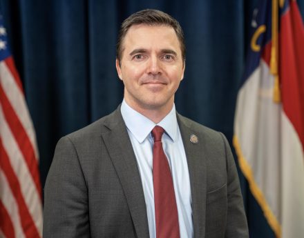 An official portrait of N.C. Attorney General Jeff Jackson. The American and North Carolina flags are shown behind him.