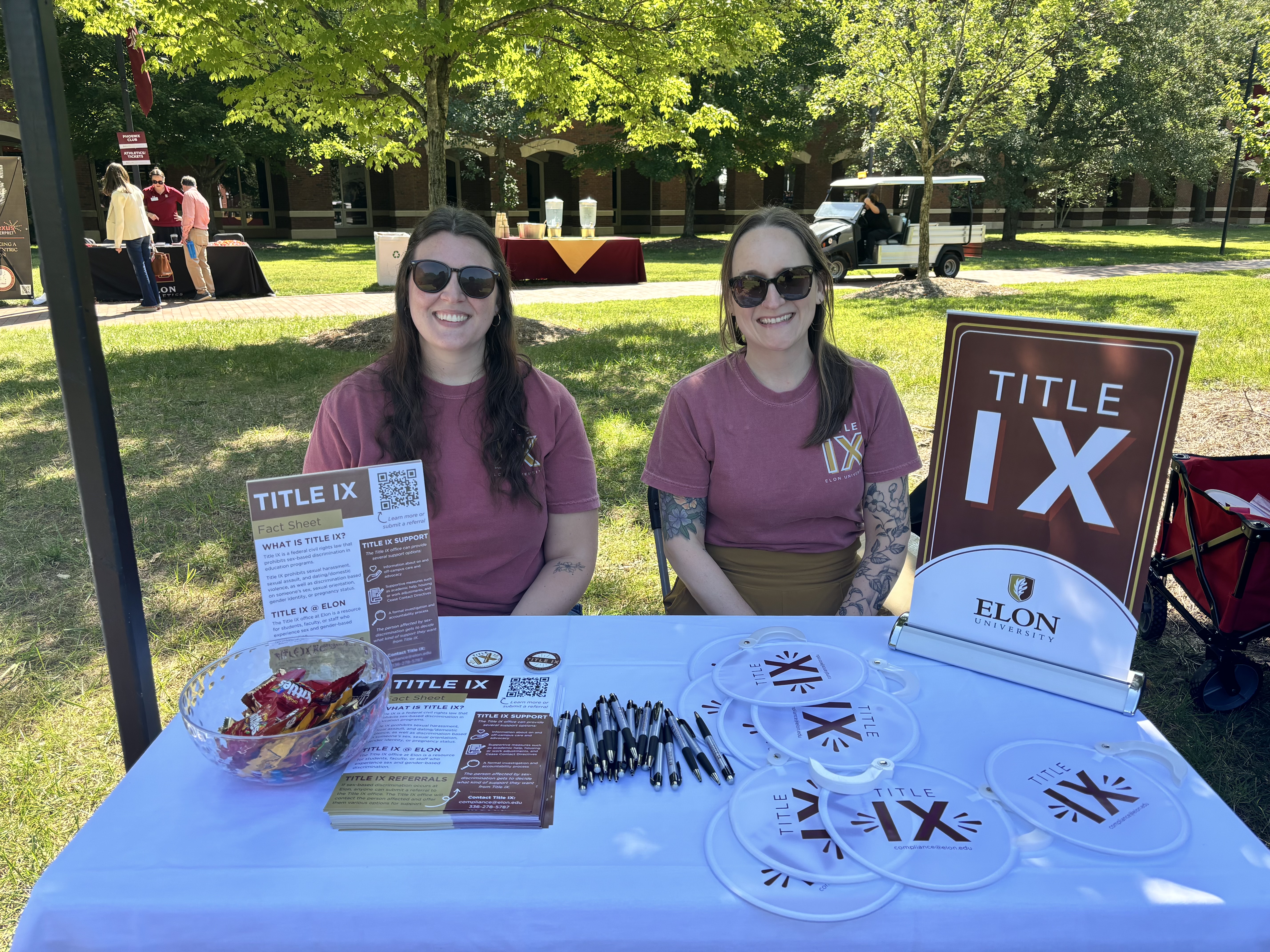 Members of the Title IX team sitting at a table with Title IX branded giveaways