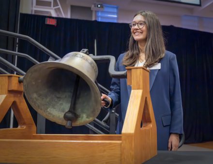 A woman rings a bell sitting between a wooden holder