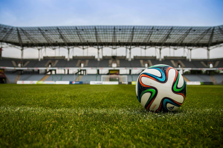 A stock image of a soccer ball on a field in an empty stadium