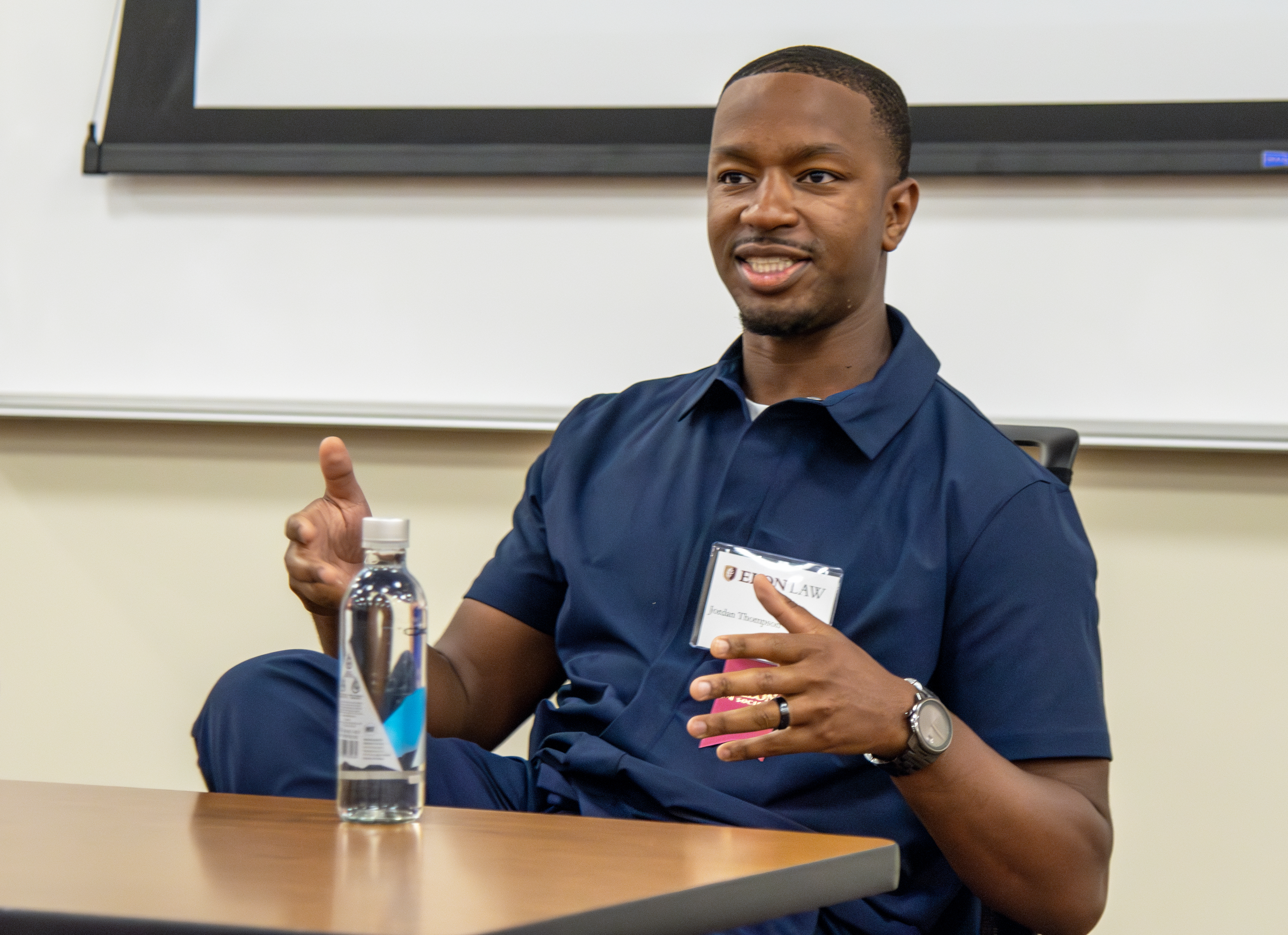 A man in a blue shirt seated at a classroom table.