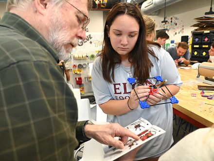 Elon professor Randy Piland huddles with Ali Steele '27