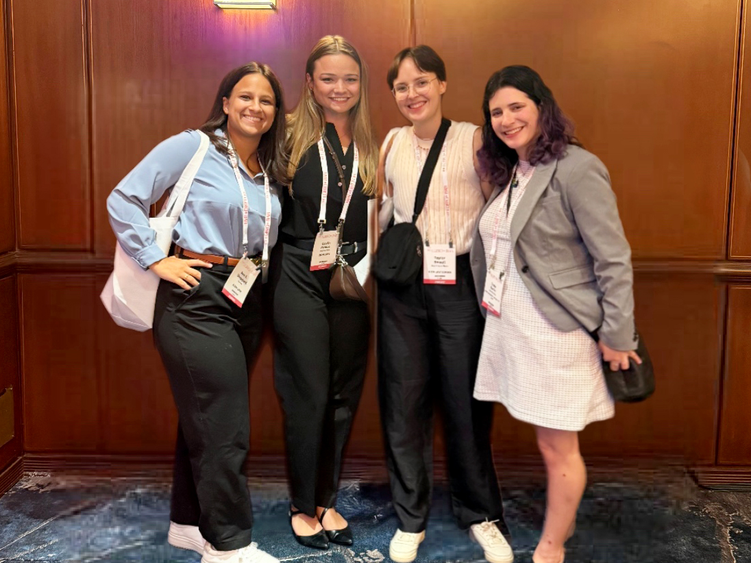 Four women posed for a group shot. They are smiling and wearing name tags.