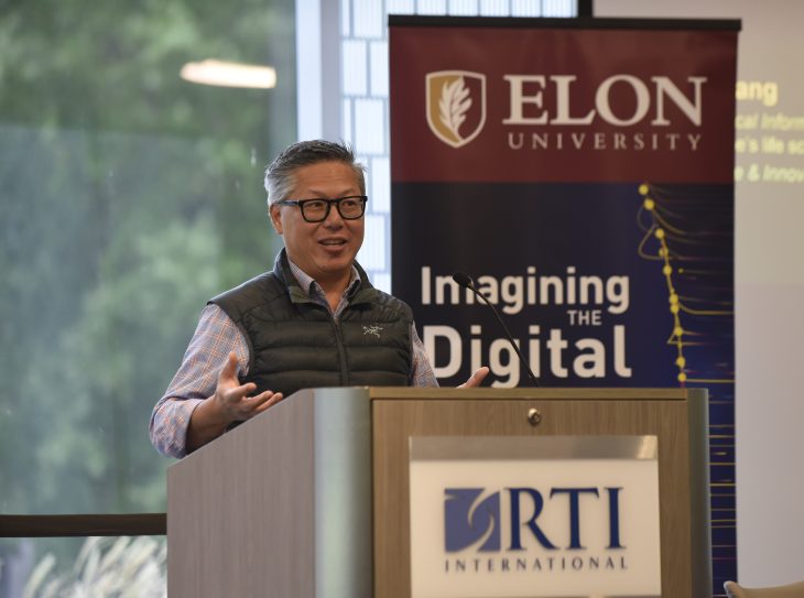 Photo of Erich Huang at a podium delivering remarks at a summit on AI co-hosted by RTI International and Elon University.