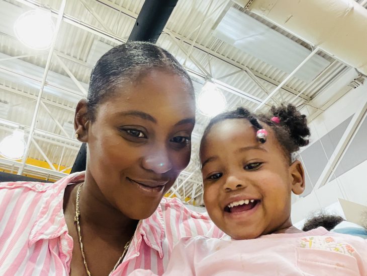 A woman and her daughter both wear light pink for a selfie photo shot from a low angle.