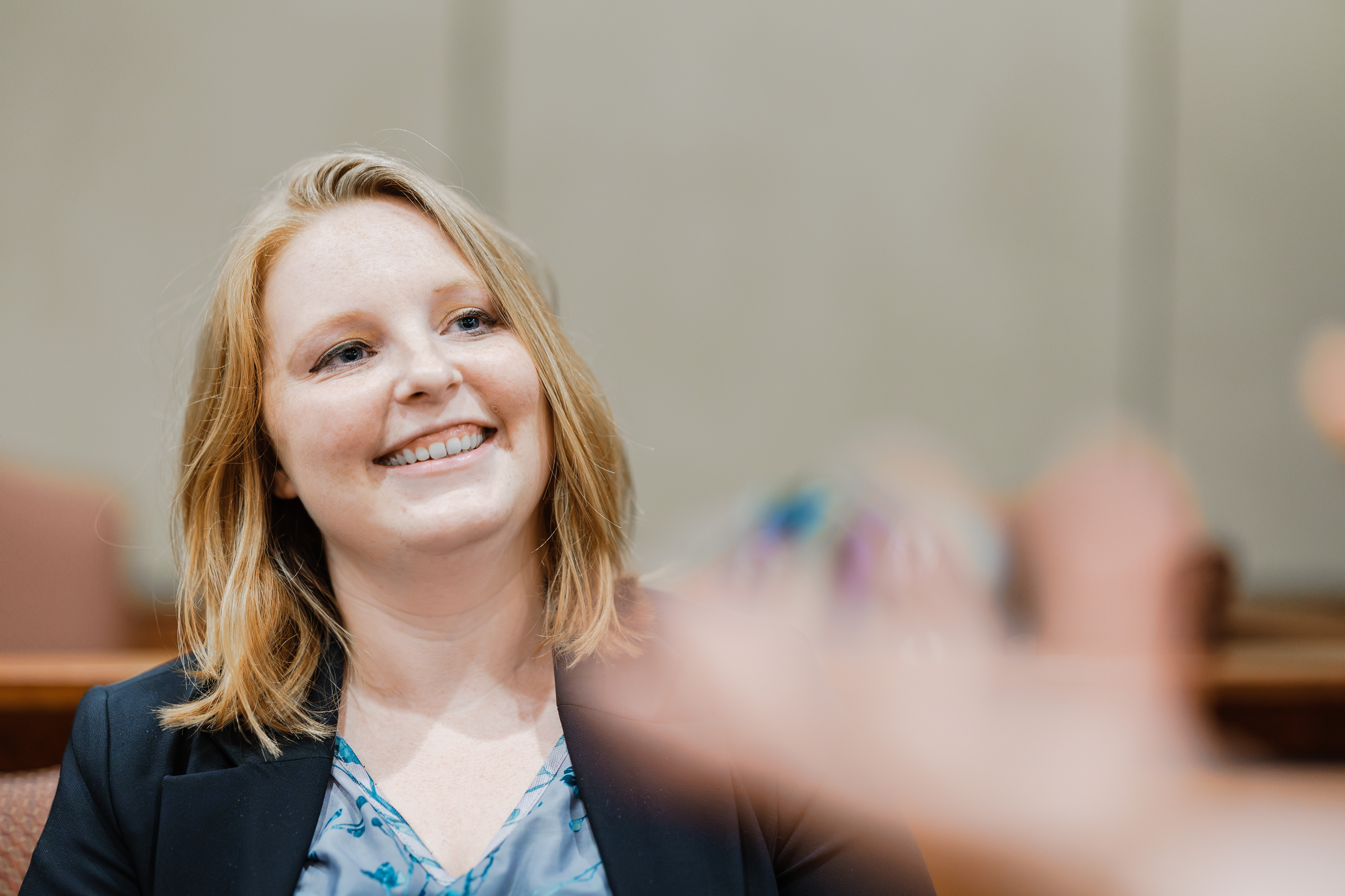Ivey Schofield smiling broadly while seated in the jury box of the Robert E Long Courtroom.