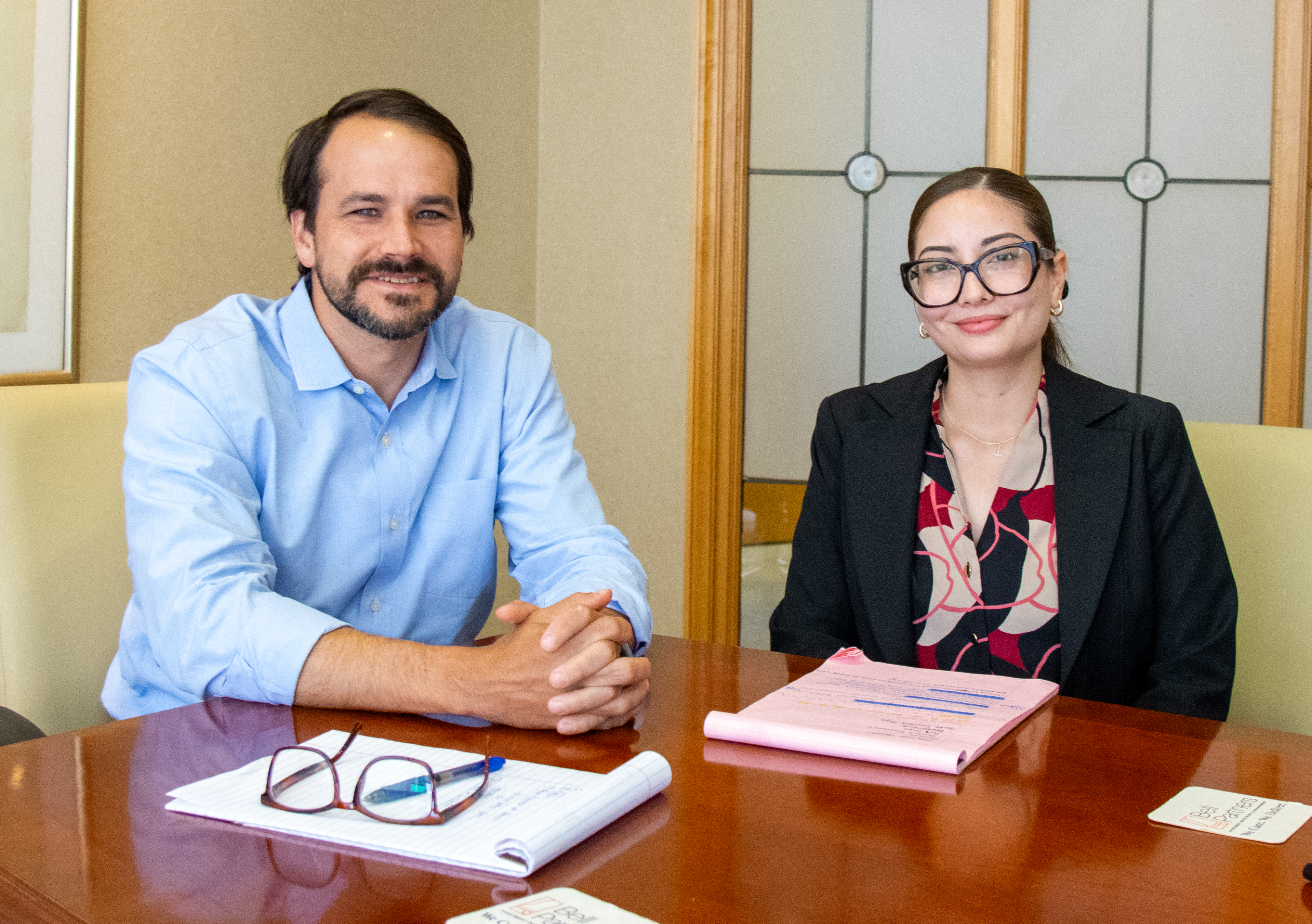Adriana Hernandez and Jack Alsup seated at a conference table. They are smiling and looking at the camera.