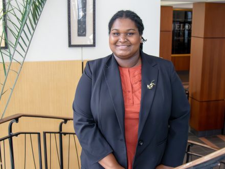 Karrington Wallace in a black suit on the spiral stairs at Elon Law