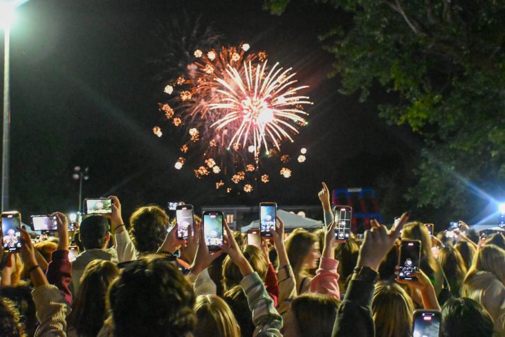 People watch a fireworks display while taking photos