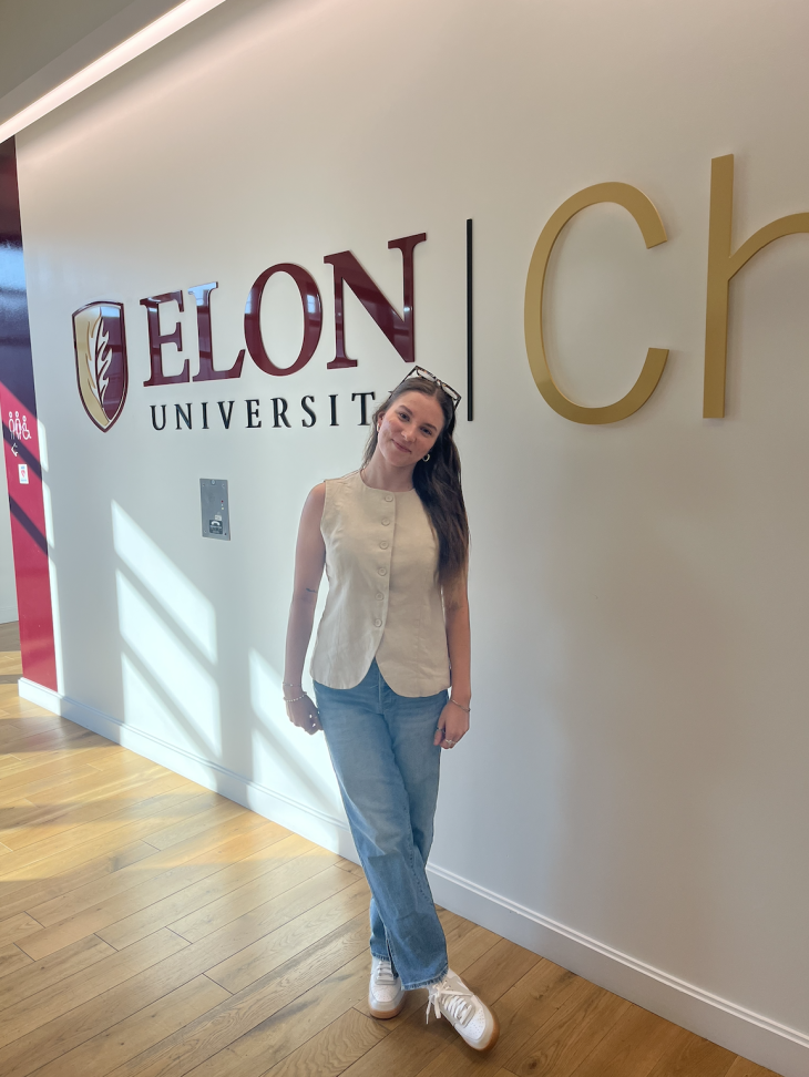 Skylar Cook stands in front of an Elon Charlotte sign