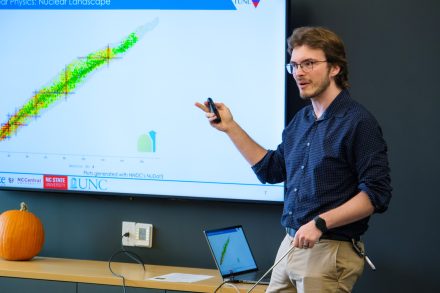 Person in blue shirt points to a presentation on a screen