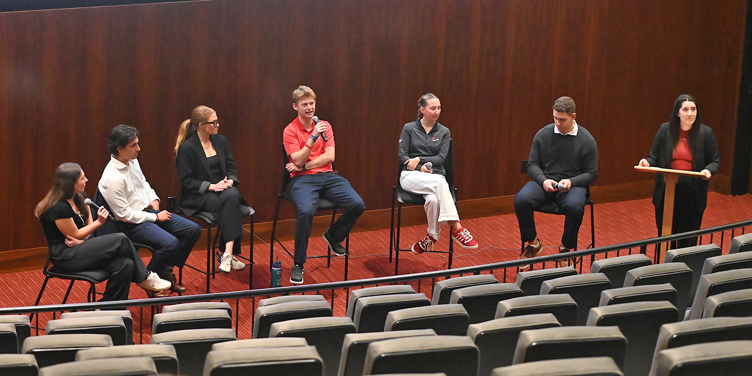 Elon student Scott Katz ’26 talks with microphone with students around him