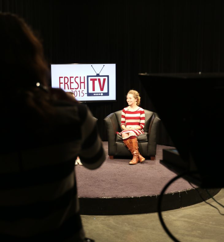 Lillian smiles facing towards her right, on set while live for FreshTV.