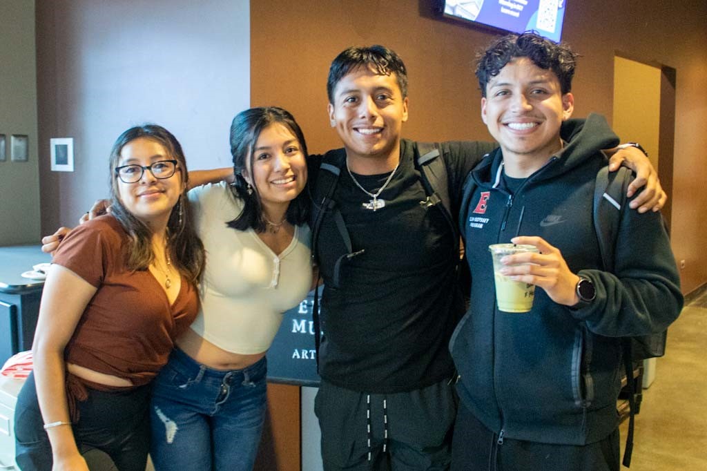 Four people pose for a photo with one holding coffee