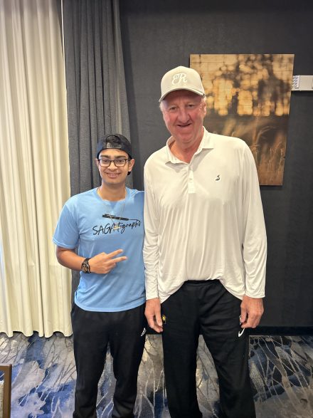 Shaan Gandhi, vestido de azul, sonríe junto a Larry Bird, vestido de blanco.