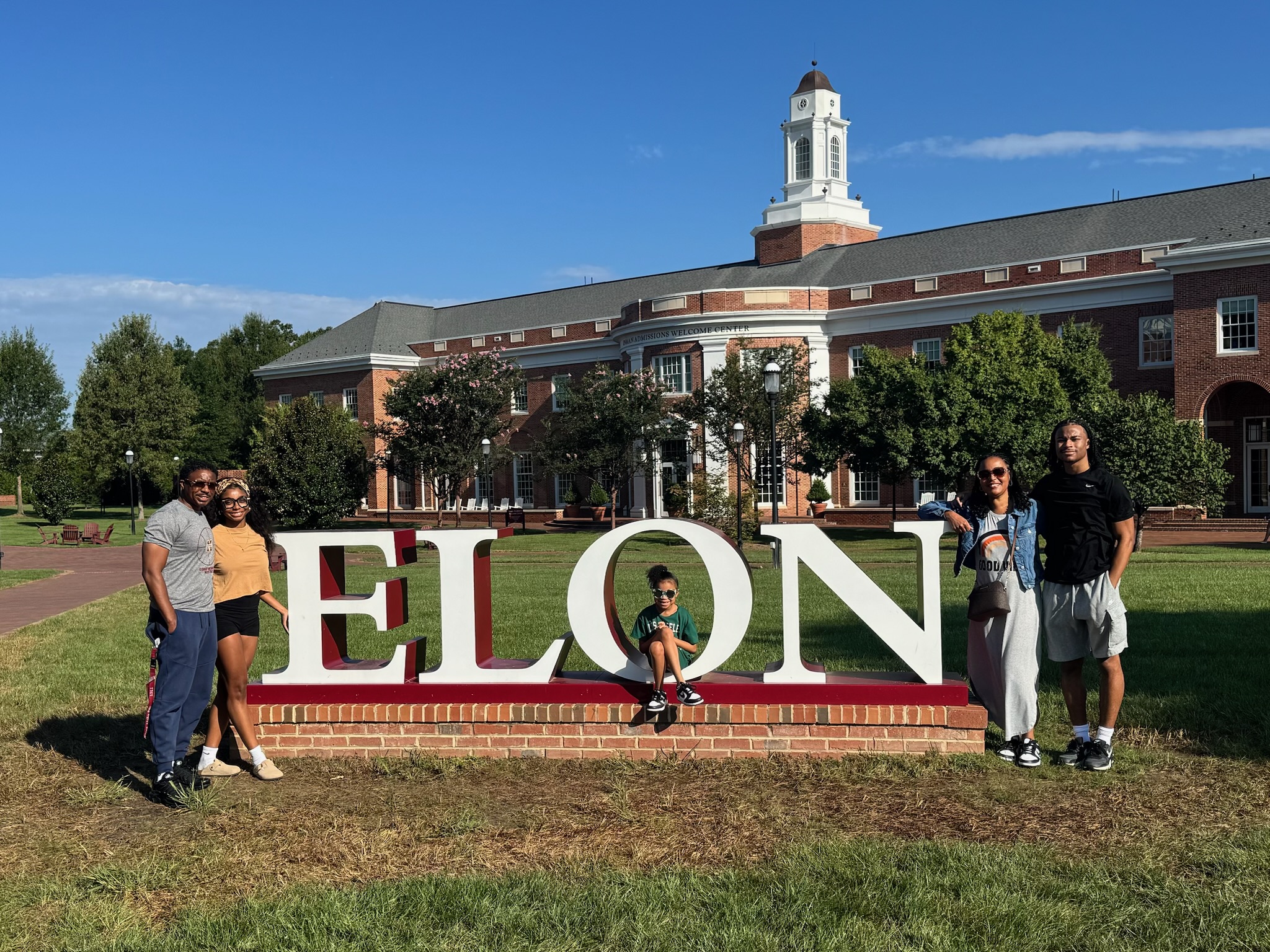 Mya Lee and her family pose at the Elon sign in front of Inman Admissions